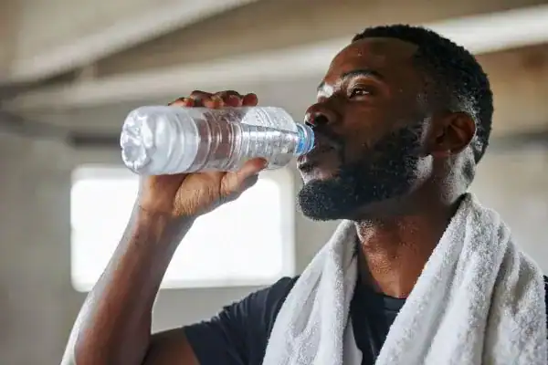 Hydration: The Secret Ingredient for a Toned Stomach and Enhanced Fitness 1 Image of man drinking water to improve hydration Daventry after work out.